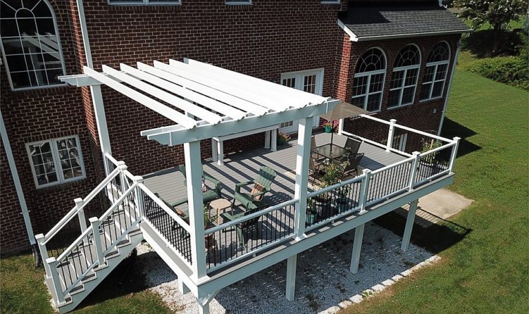 Trex Select Pebble Gray Composite Deck with Trex Composite Railing with black aluminum balusters and a White Vinyl Pergola