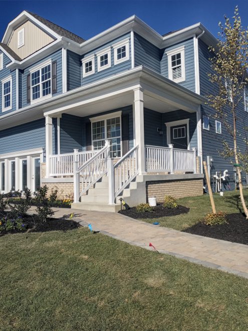 A front yard porch with white vinyl railing
