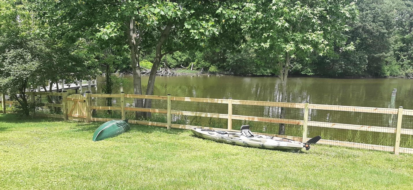 Pressure treated 3-rail ranch rail fence with black mesh and single arched gate-min