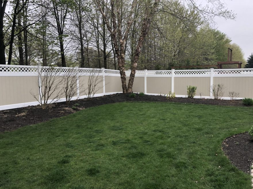 Two toned tan and white vinyl privacy fence with lattice topper